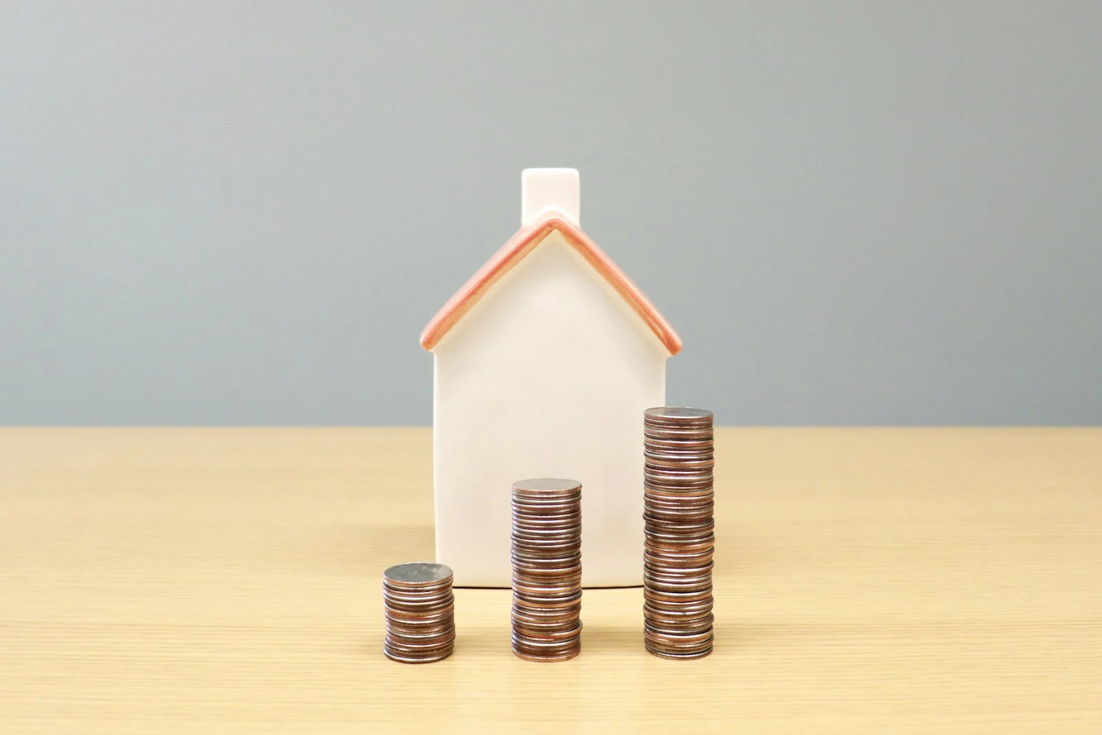 Hausmodell neben Münzstapeln – Symbolbild für Eigenkapital beim Immobilienkauf