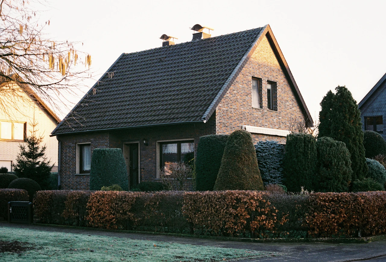 Klinkerhaus mit Hecke am Niederrhein – Symbolbild für ein geerbtes Elternhaus