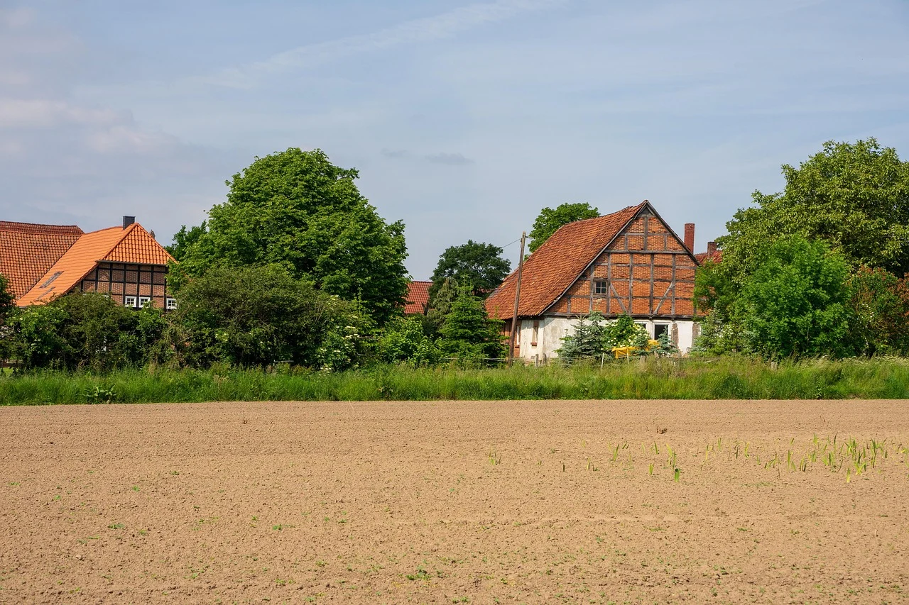 Älteres Bauernhaus mit Fachwerk am Feldrand – Symbolbild für Jung kauft Alt